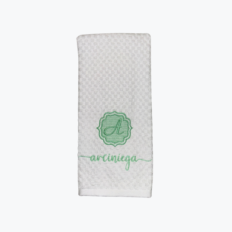White textured dishtowel with green monogram and name on a white background